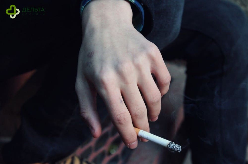 Парень держит в руках сигарету